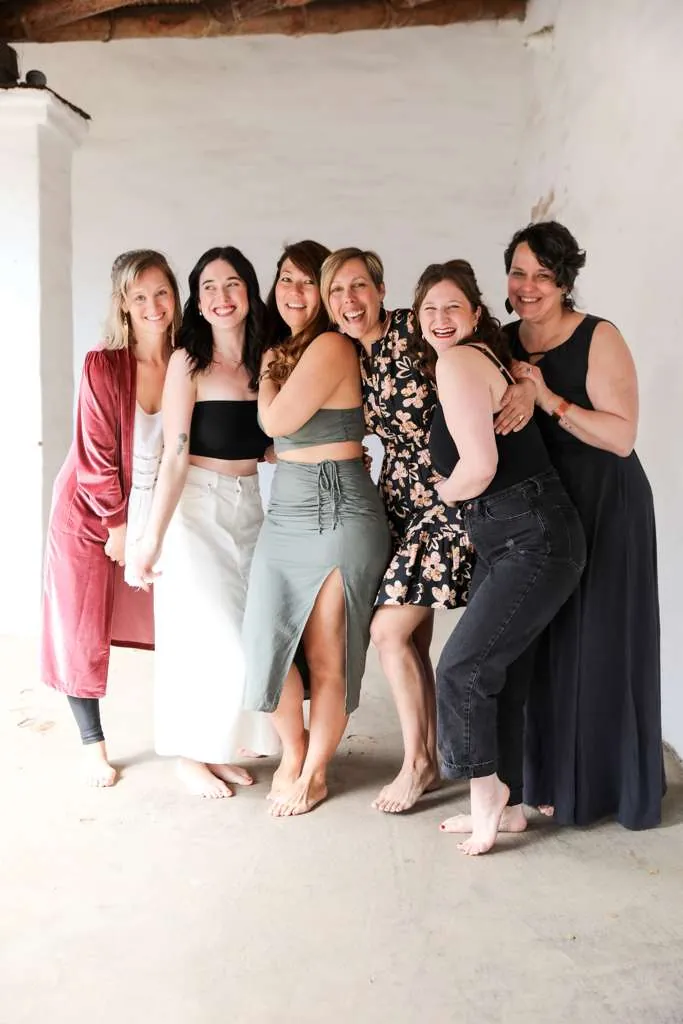 A row of women leaning into each other, laughing